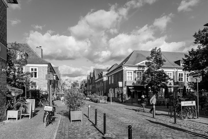 Schwarz-Weiß-Foto zeigt breite Kopfsteinpflasterstraße mit Blick auf die angrenzenden kleinen Häuser