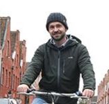 Mann steht mit Rad auf Straße im Holländischen Viertel